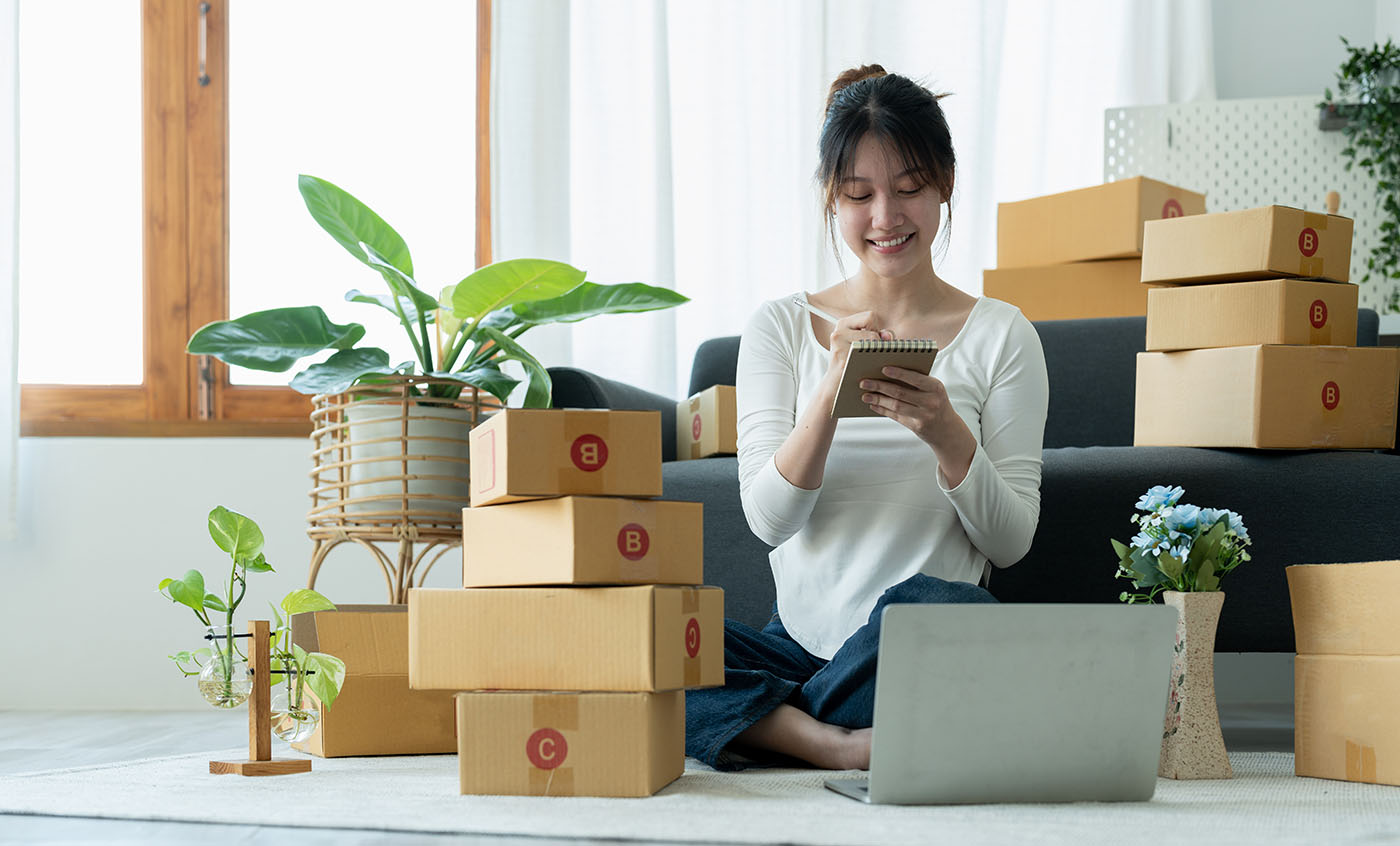 Startup small business owner working with computer at workplace. Freelance woman seller check product order. Packing goods for delivery to customer. Online selling. E-commerce